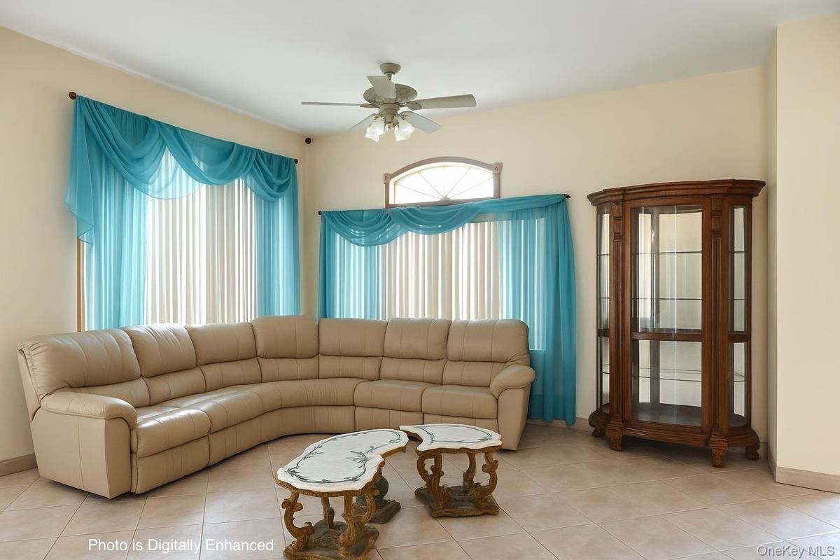 Living area featuring tile patterned floors and ceiling fan