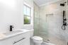 Bathroom with healthy amount of natural light, a marble finish shower, toilet, crown molding, and vanity