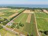Aerial view of sparsely populated area with large plots for crops, property boundaries highlighted, and a large body of water