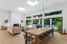 Dining room featuring a towering ceiling, a brick fireplace, light wood finished floors, recessed lighting, and a skylight