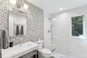Bathroom featuring walk in shower, recessed lighting, and tile walls
