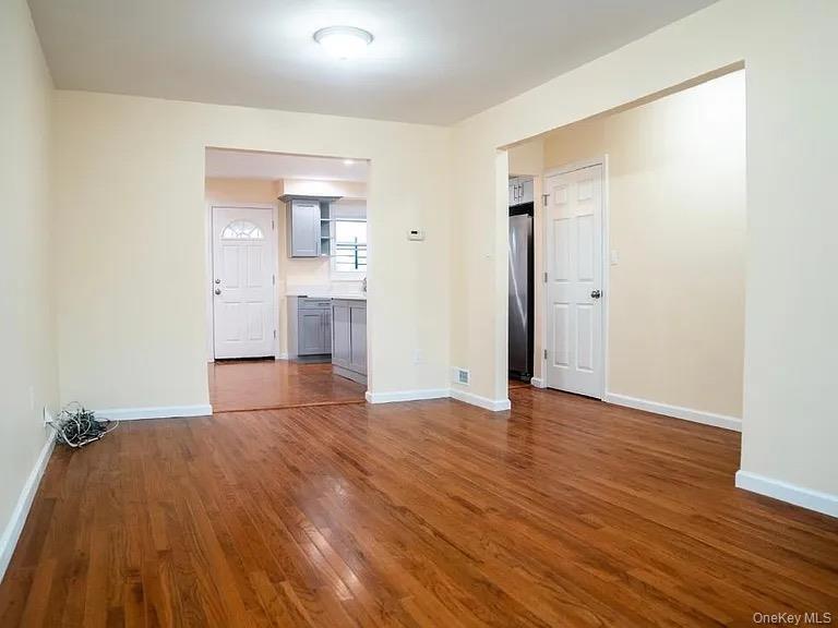 Empty room featuring dark wood-style flooring and baseboards