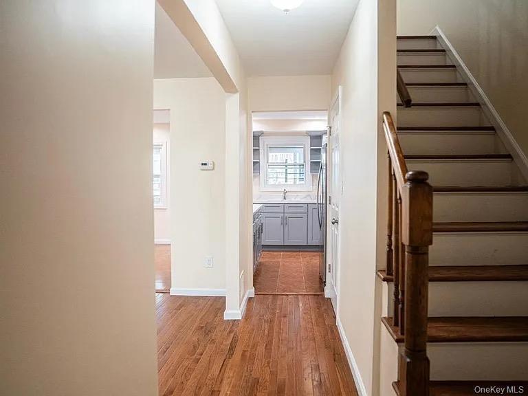 Hall featuring a sink, light wood-type flooring, baseboards, and stairs