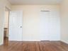 Unfurnished bedroom with wood finished floors, a closet, and baseboards