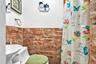 Full bath with toilet, tile walls, a sink, and a shower with shower curtain