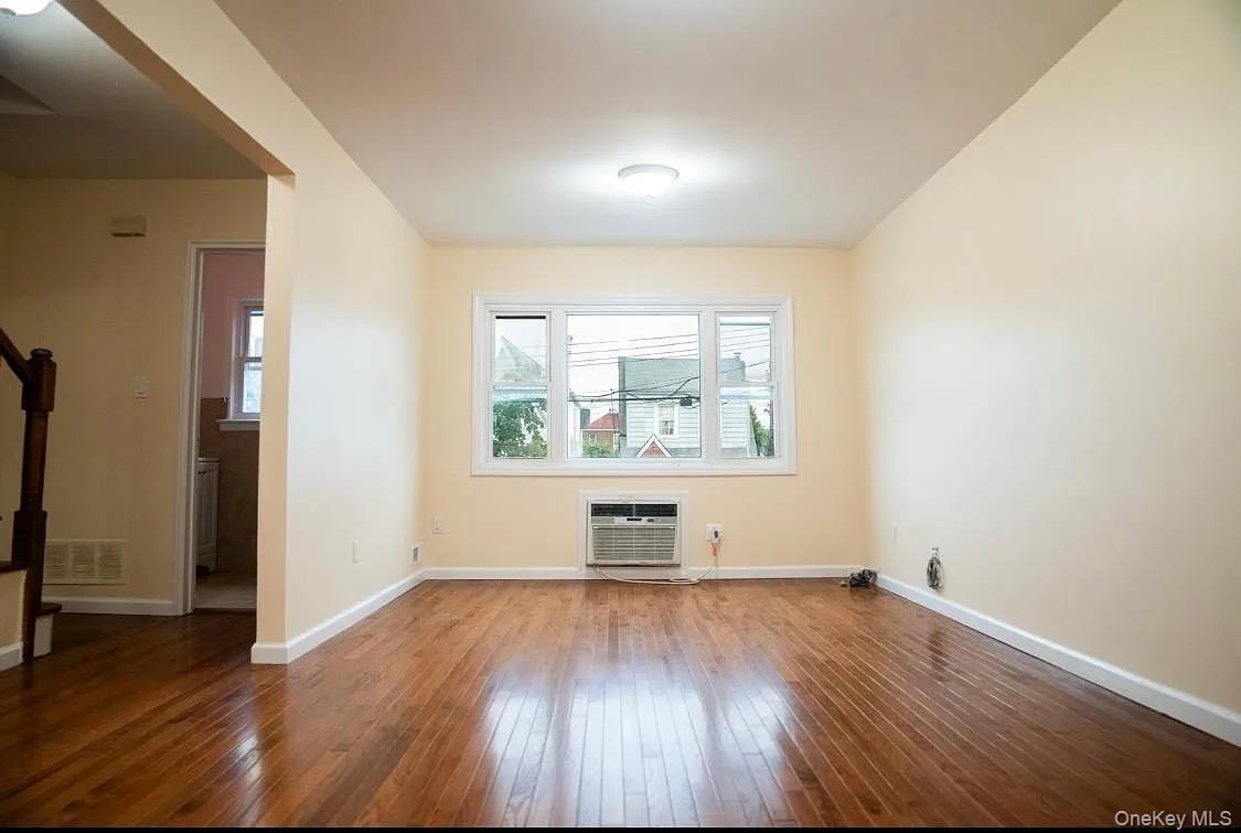 Empty room featuring baseboards, visible vents, a wall unit AC, and hardwood / wood-style flooring