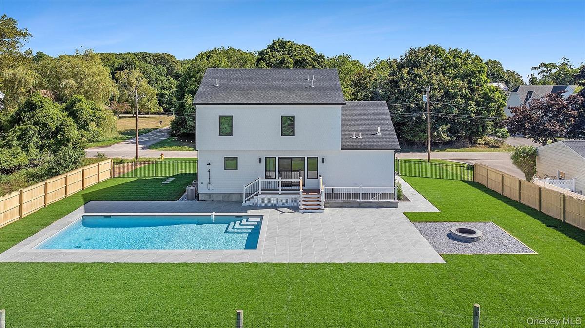 Back of property with a patio, a fire pit, roof with shingles, and a fenced backyard