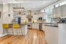 Kitchen featuring wall chimney exhaust hood, appliances with stainless steel finishes, a kitchen bar, light wood-type flooring, and a sink