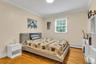 Bedroom with baseboard heating, ornamental molding, and light wood finished floors