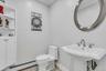 Half bath featuring a baseboard radiator, tile patterned flooring, crown molding, toilet, and a sink