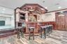 Indoor wet bar featuring a wall unit AC, a wainscoted wall, wood finished floors, a decorative wall, and ornamental molding