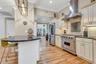 Kitchen with exhaust hood, stainless steel appliances, crown molding, cream cabinets, and a breakfast bar