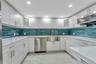 Kitchen with appliances with stainless steel finishes, a sink, tasteful backsplash, glass insert cabinets, and recessed lighting