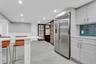 Kitchen with stainless steel refrigerator with ice dispenser, a breakfast bar, recessed lighting, wainscoting, and light marble finish flooring