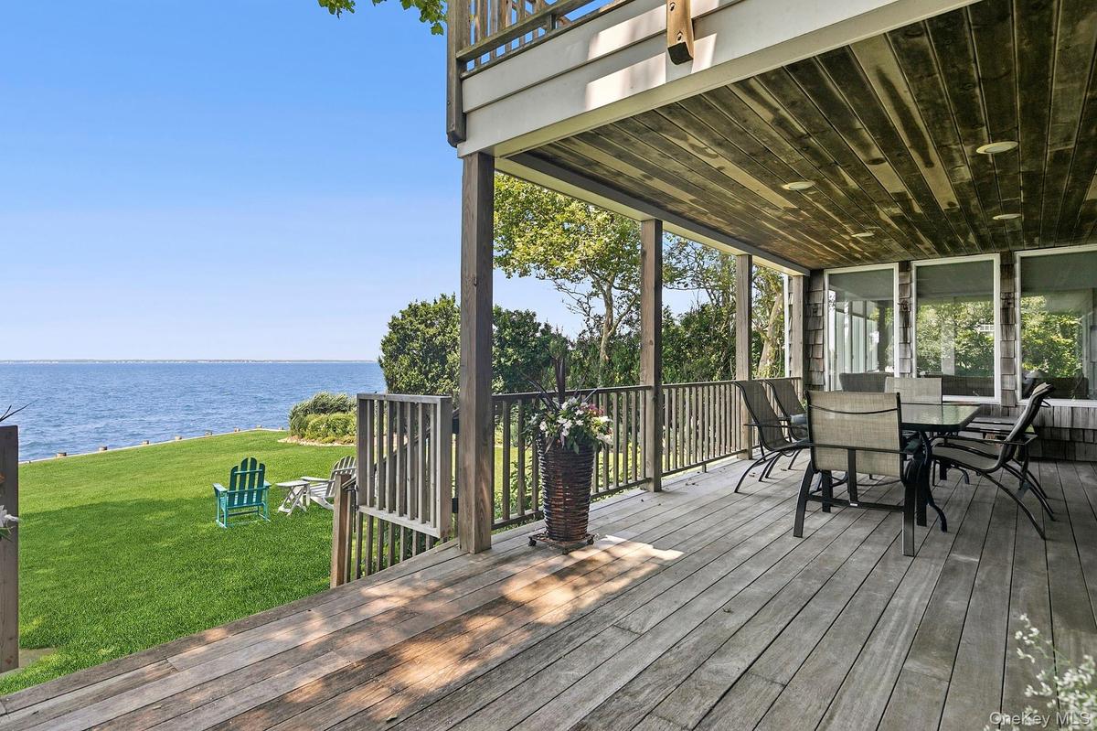 Deck featuring a water view, a lawn, and outdoor dining area