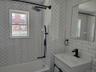 Bathroom featuring shower / tub combination, vanity, and tile walls