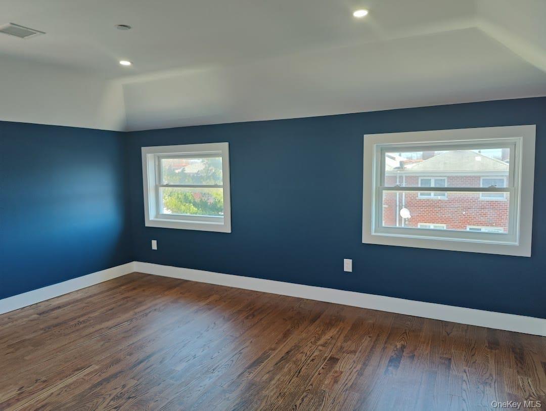 Empty room with dark wood-style floors and recessed lighting