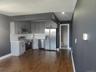 Kitchen with appliances with stainless steel finishes, dark wood-style floors, tasteful backsplash, light stone countertops, and white cabinetry
