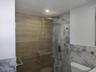 Full bathroom with a shower stall and tile walls