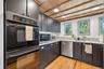 Kitchen featuring stainless steel appliances, wooden ceiling, light wood finished floors, dark cabinets, and light stone countertops