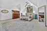 Carpeted bedroom featuring an AC wall unit and high vaulted ceiling