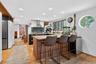 Kitchen featuring a peninsula, recessed lighting, a kitchen bar, light wood-style floors, and light stone counters