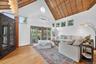 Living room with high vaulted ceiling, healthy amount of natural light, wood ceiling, light wood-style floors, and a wall mounted AC