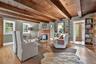 Living area with hardwood / wood-style floors, a wood ceiling with exposed beams, and a brick fireplace