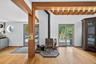 Living room with a wood stove, wood finished floors, plenty of natural light, and a wooden ceiling with exposed beams