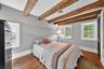 Bedroom featuring dark wood-style flooring and beamed ceiling