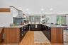 Kitchen with a peninsula, a breakfast bar, light wood-style flooring, light stone counters, and recessed lighting