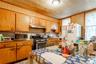 Kitchen featuring appliances with stainless steel finishes, brown cabinetry, wooden walls, under cabinet range hood, and light countertops