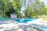View of pool featuring a patio, view of wooded area, and a storage shed
