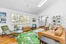 Living room with baseboard heating, high vaulted ceiling, a skylight, and hardwood / wood-style floors
