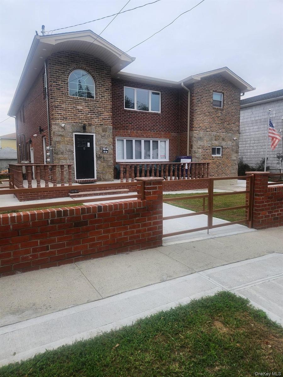 View of front facade with brick siding, stone siding, and a patio area