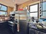 Kitchen with stainless steel refrigerator with ice dispenser, wall chimney range hood, range with gas stovetop, backsplash, and tile walls