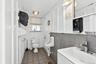 Half bath with light tile patterned floors, tile walls, and vanity