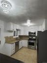 Kitchen featuring white cabinetry, stainless steel appliances, tasteful backsplash, and dark stone counters