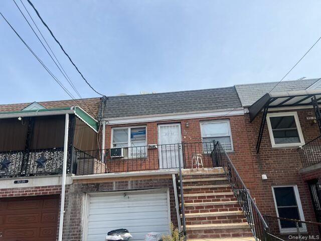 View of front of property featuring a balcony, brick siding, a shingled roof, stairs, and an attached garage