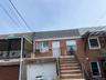 View of front of property featuring a balcony, brick siding, a shingled roof, stairs, and an attached garage