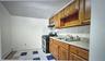 Kitchen featuring backsplash, brown cabinetry, a baseboard heating unit, gas range, and light countertops