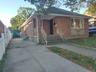 Bungalow with brick siding, a chimney, and concrete driveway