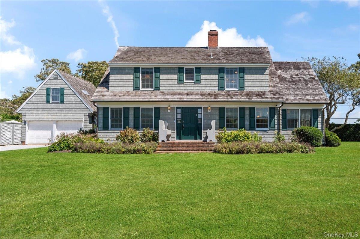 View of front of home featuring a front lawn, a chimney, and driveway