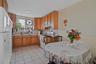 Kitchen with white appliances, under cabinet range hood, backsplash, and light countertops