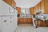 Kitchen featuring white appliances, under cabinet range hood, light countertops, and brown cabinets