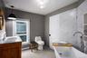 Bathroom featuring a soaking tub, double vanity, tile walls, and baseboard heating
