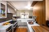 Kitchen featuring exhaust hood, stainless steel appliances, light wood-style floors, and light stone counters
