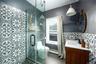Full bath with vanity, a shower stall, tile patterned floors, a baseboard heating unit, and tile walls