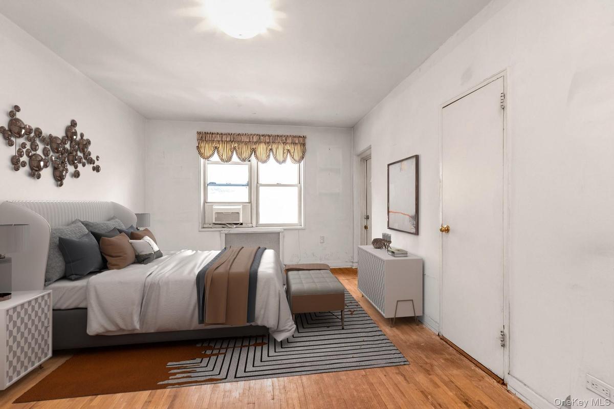 Bedroom featuring wood finished floors and radiator heating unit - Virtually Staged