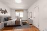 Bedroom featuring wood finished floors and radiator heating unit - Virtually Staged